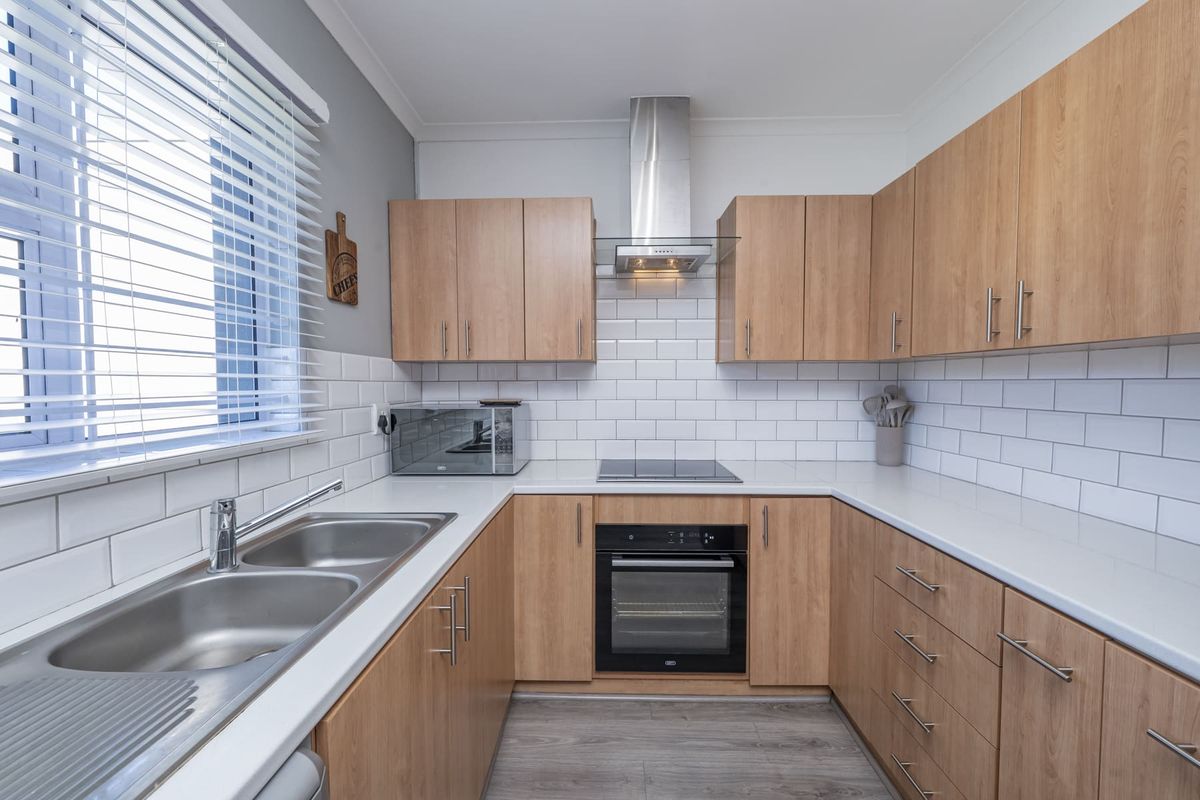 Modern kitchen featuring light wood-tone cabinetry, white subway tile backsplash, stainless steel appliances, and a double bowl sink with ample counter space.