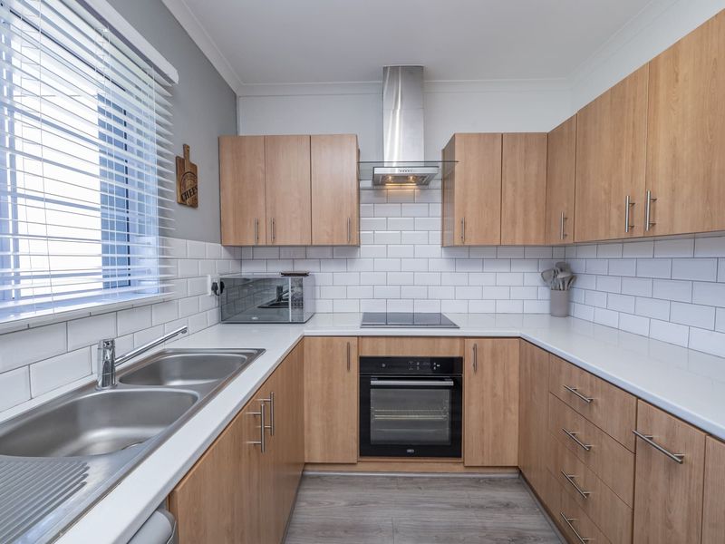 Modern kitchen featuring light wood-tone cabinetry, white subway tile backsplash, stainless steel appliances, and a double bowl sink with ample counter space.