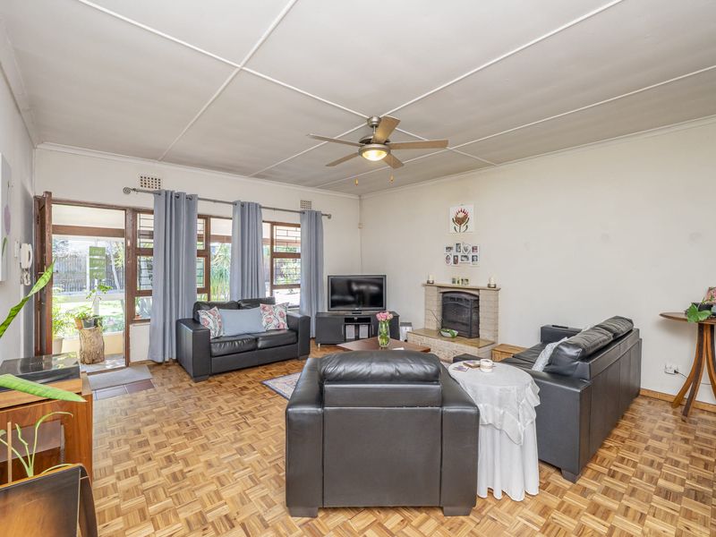 Spacious living room featuring classic parquet flooring, a built-in fireplace, and direct access to the outdoor area through a sliding glass door.