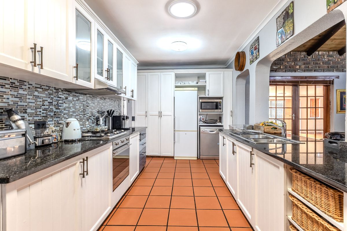 A well-appointed kitchen featuring granite countertops, mosaic tile backsplash, built-in oven, gas hob, and ample cabinetry with a functional layout.