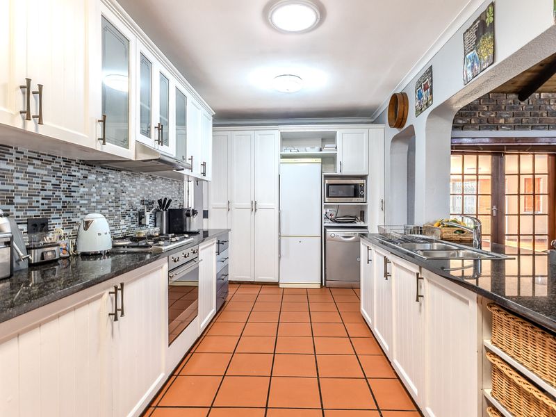 A well-appointed kitchen featuring granite countertops, mosaic tile backsplash, built-in oven, gas hob, and ample cabinetry with a functional layout.