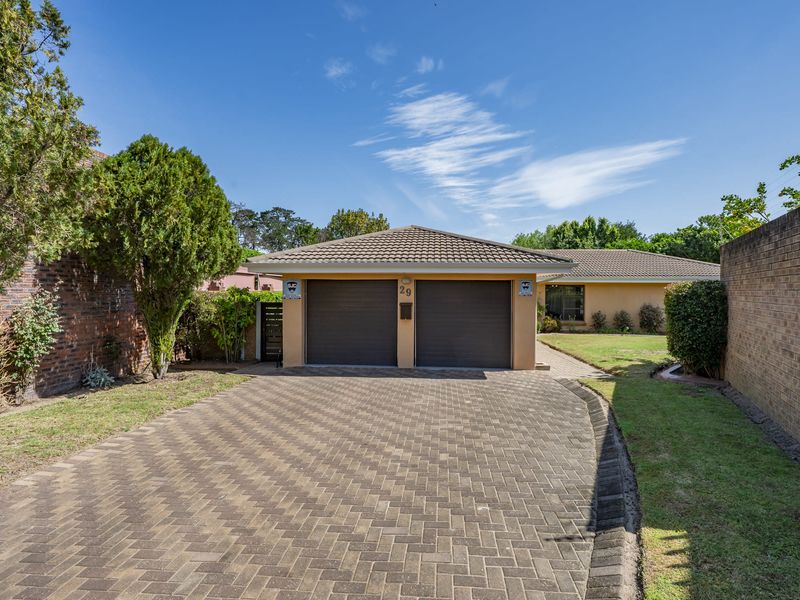 Front view of the property featuring a double garage, paved driveway, and well-maintained garden area.