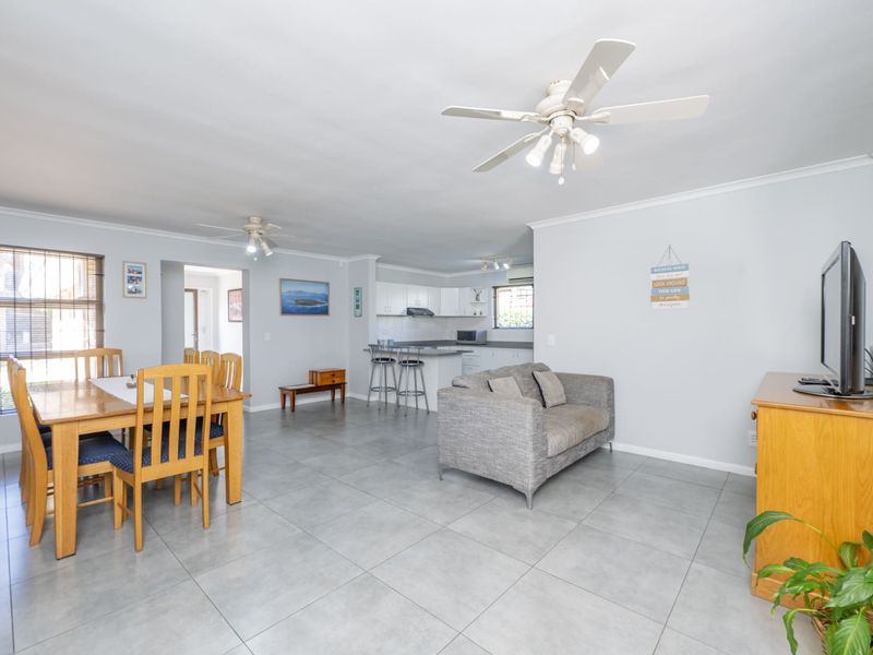 Open-plan living and dining area featuring tiled flooring, ceiling fans, and a functional kitchen with built-in cabinetry and countertops.