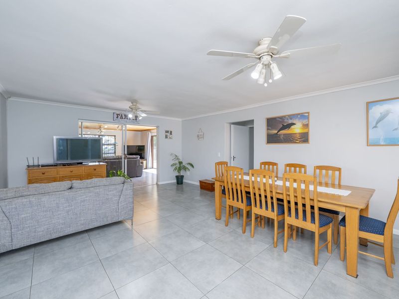Spacious open-plan living and dining area featuring neutral tiled flooring, ceiling fans, and direct access to an adjoining sunroom.