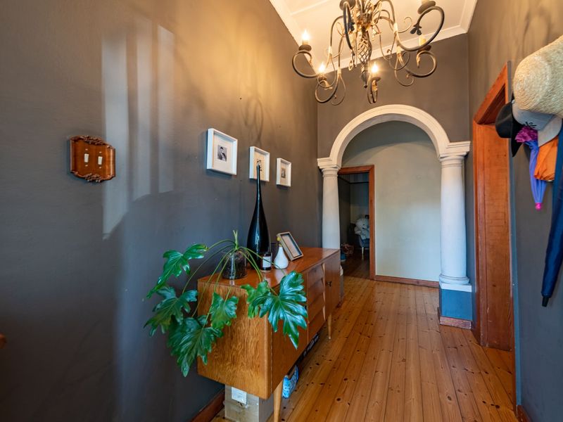 A characterful hallway featuring polished timber flooring, a decorative archway with columns, and classic coving details.