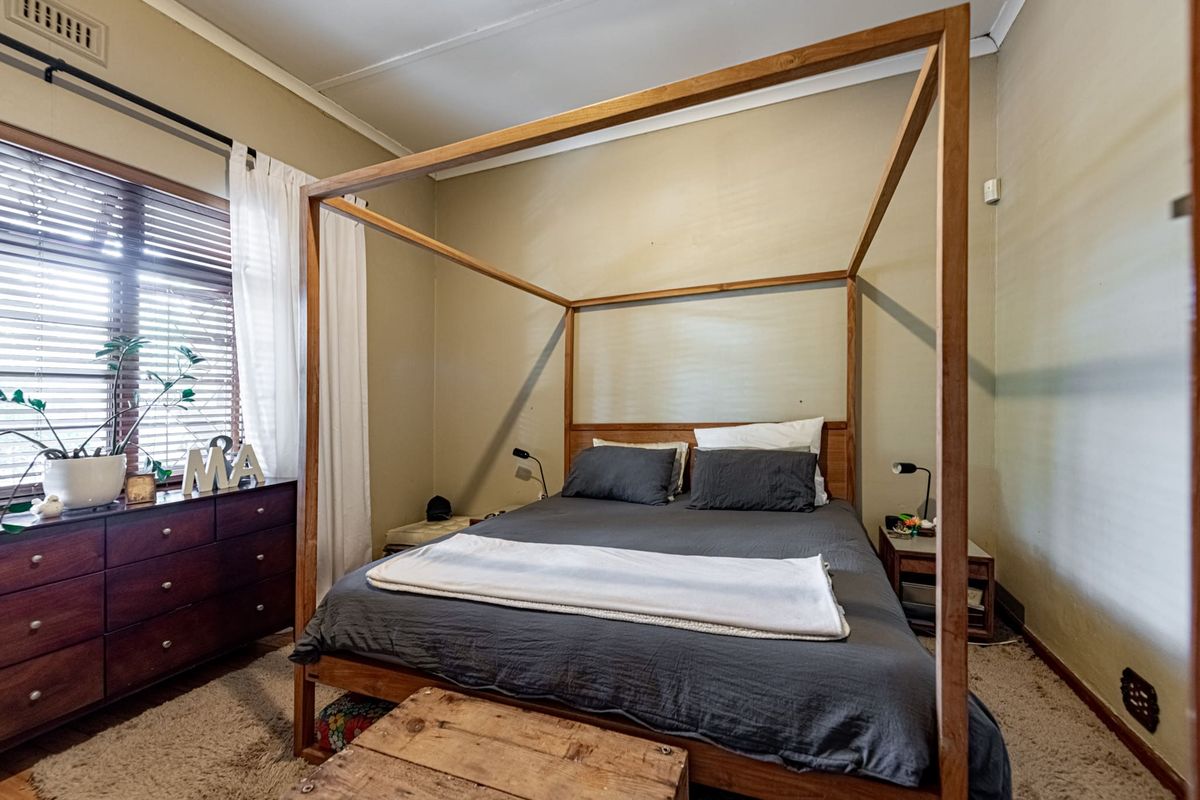 A bedroom featuring carpeted flooring, venetian blinds, and neutral wall tones, offering a functional space ready for cosmetic updates.