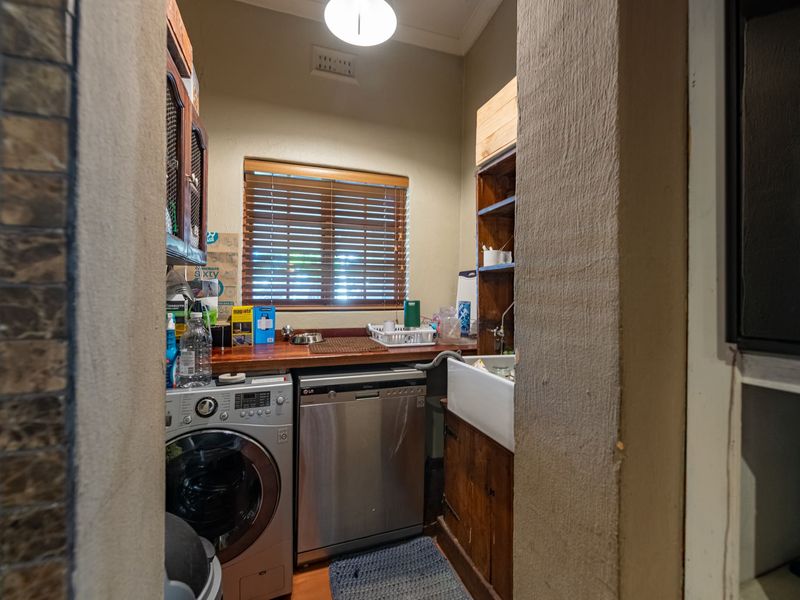 A functional scullery area featuring a classic butler sink, wooden countertops, and dedicated space for laundry and dishwashing appliances.