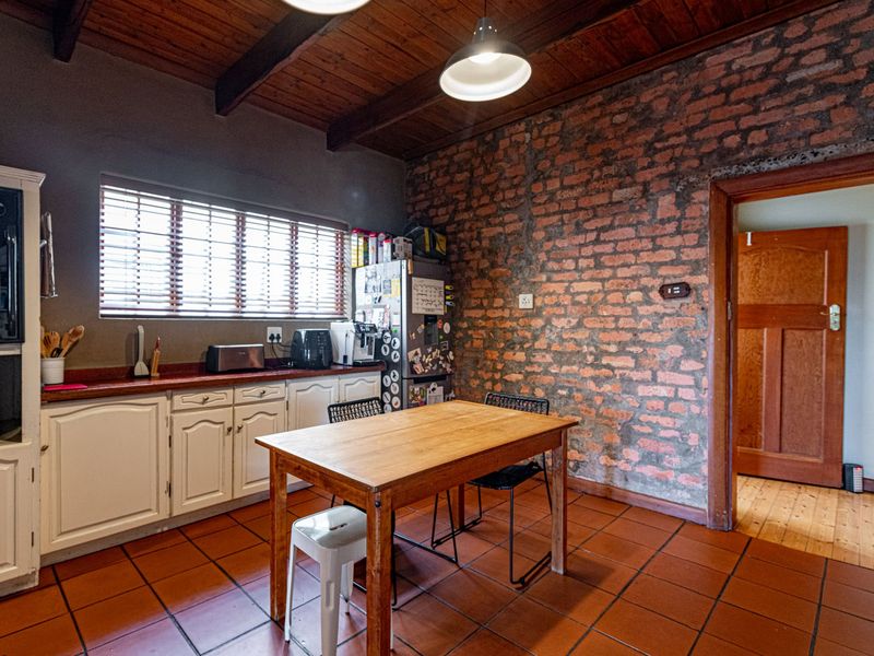 Rustic kitchen featuring exposed brick walls, timber beamed ceilings, terracotta floor tiles, and traditional cabinetry with integrated oven.