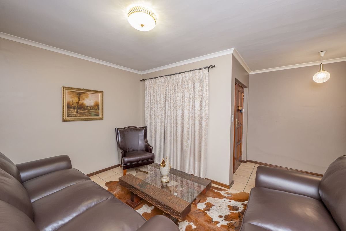 A comfortable living room featuring tiled flooring, cove cornicing, and a combination of flush mount and pendant lighting.