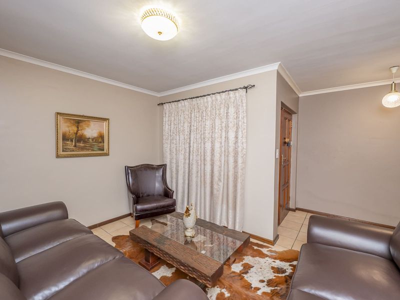 A comfortable living room featuring tiled flooring, cove cornicing, and a combination of flush mount and pendant lighting.
