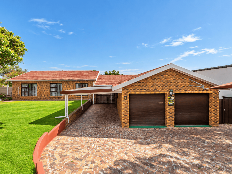 Front view of a well-maintained face brick house featuring a double garage, paved driveway, carport, and a neat front lawn.