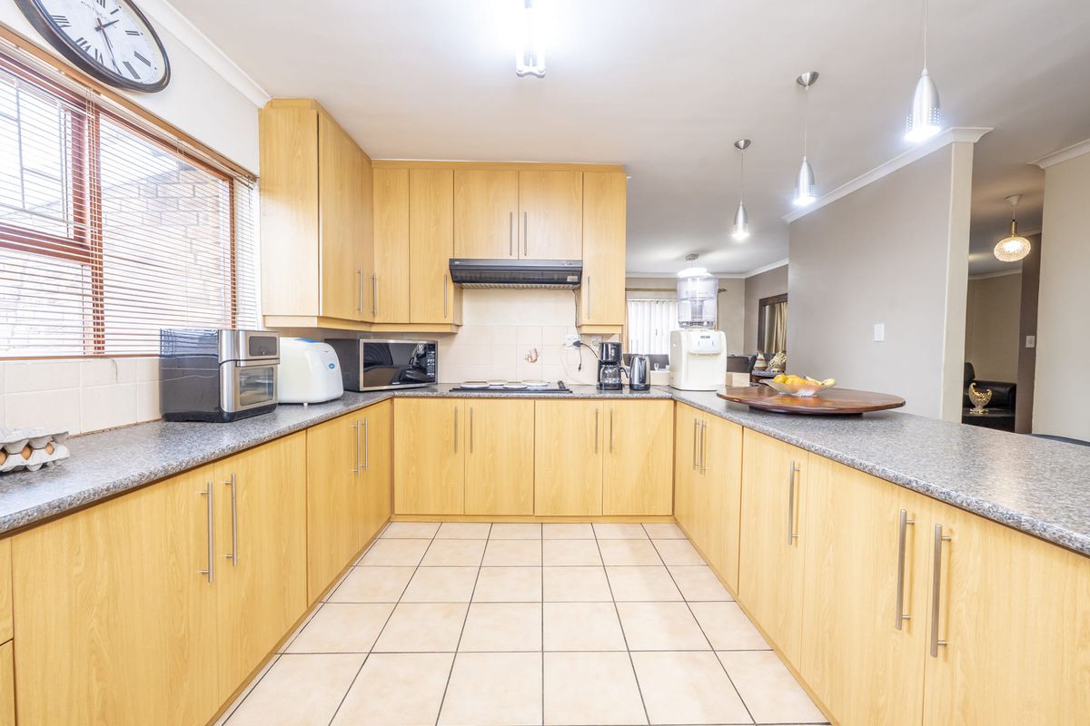 A functional kitchen featuring light wood-finish cabinetry, granite countertops, tiled flooring, and a breakfast bar, offering a practical layout for daily meal preparation.