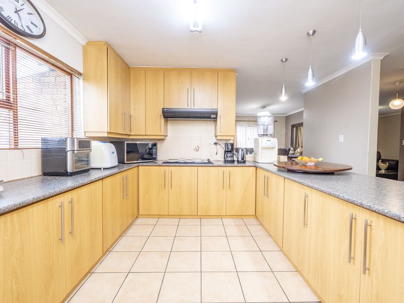 A functional kitchen featuring light wood-finish cabinetry, granite countertops, tiled flooring, and a breakfast bar, offering a practical layout for daily meal preparation.