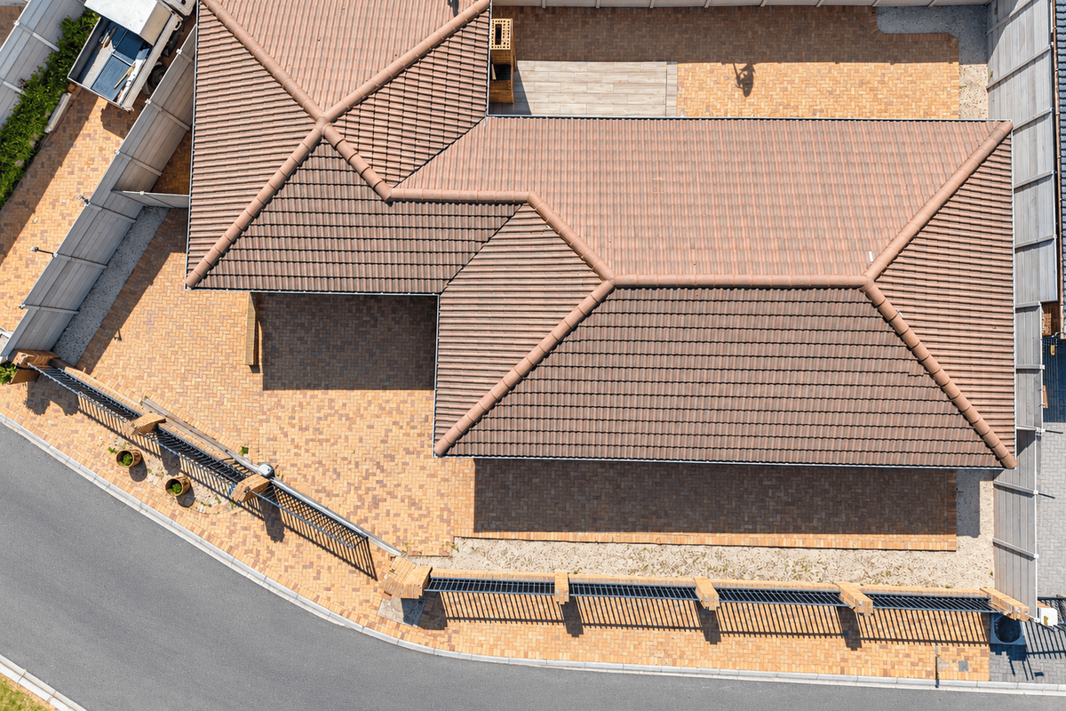 Aerial view of the property showcasing the tiled roof, extensive paved driveway, and secure perimeter fencing with a built-in outdoor braai area.