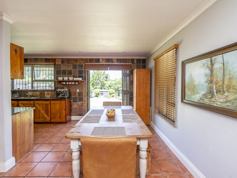 Open-plan kitchen and dining area featuring rustic wooden cabinetry, granite countertops, slate tile accents, and direct access to the outdoor patio through folding doors.