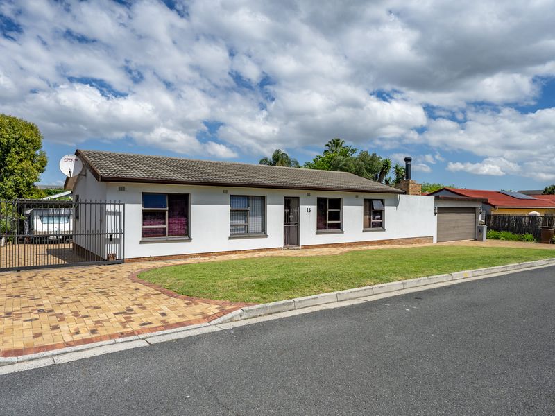 A well-maintained single-story residential property featuring a tiled roof, brick-paved driveway, secure metal gate, and an attached garage.