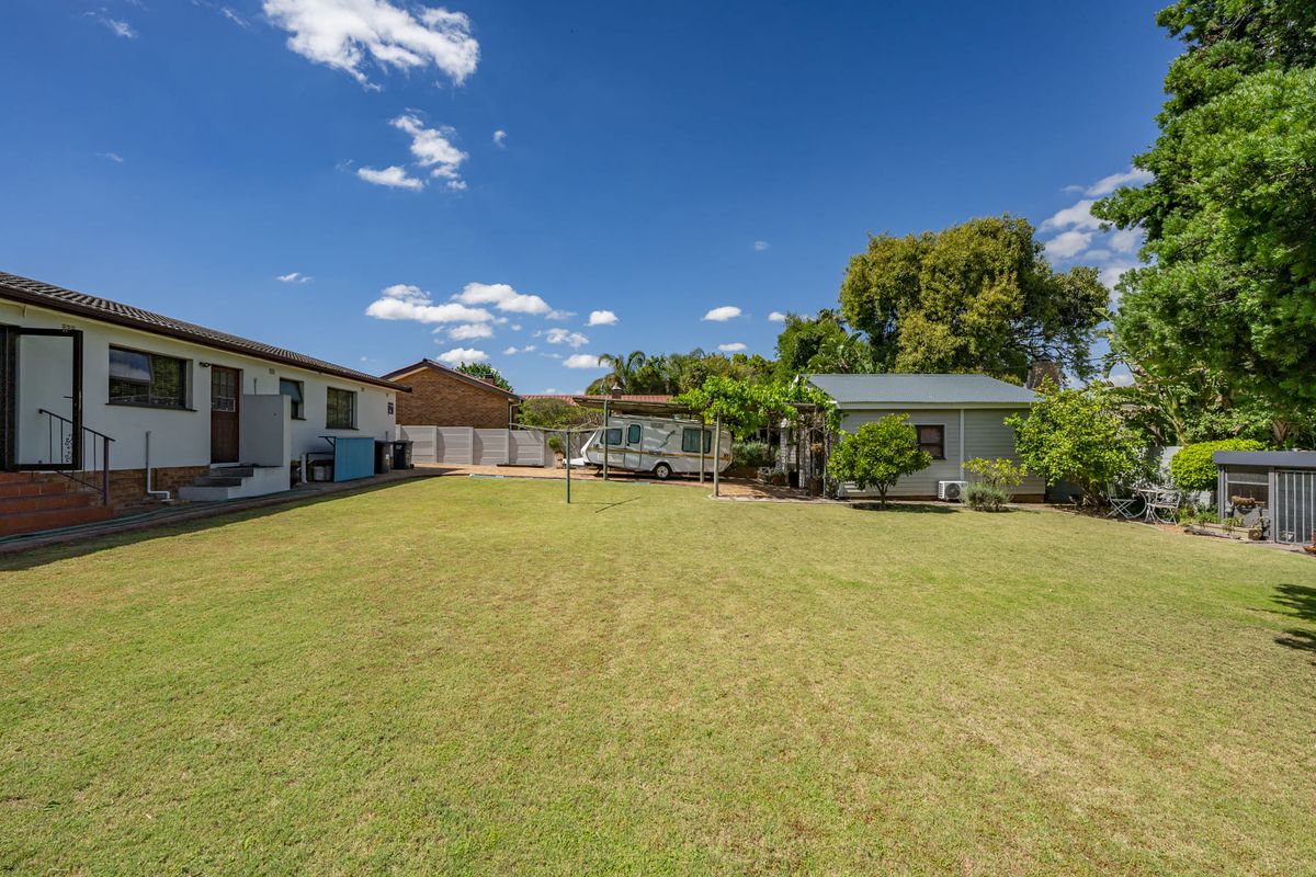 Spacious rear garden featuring a well-maintained lawn, a pergola, and a detached outbuilding, providing ample outdoor space and utility.