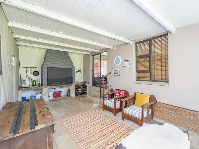 Covered outdoor patio featuring a built-in braai, stone flooring, and exposed beam ceiling, providing a functional space for outdoor entertaining.