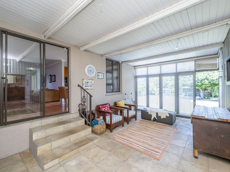 A covered patio area featuring tiled flooring, stone steps, and large sliding glass doors providing seamless access to the interior living space.