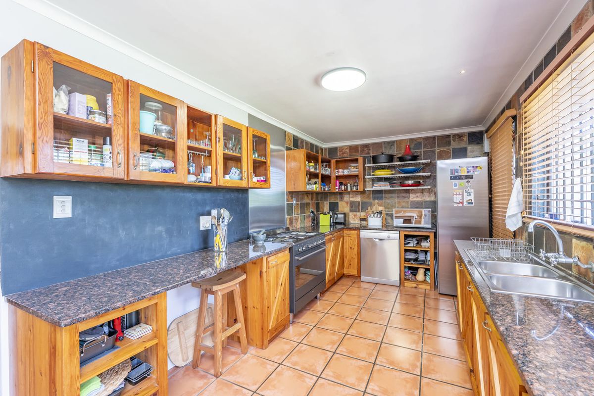 A functional kitchen featuring granite countertops, wooden cabinetry, tiled backsplash, and integrated appliances, offering a classic layout with ample storage space.