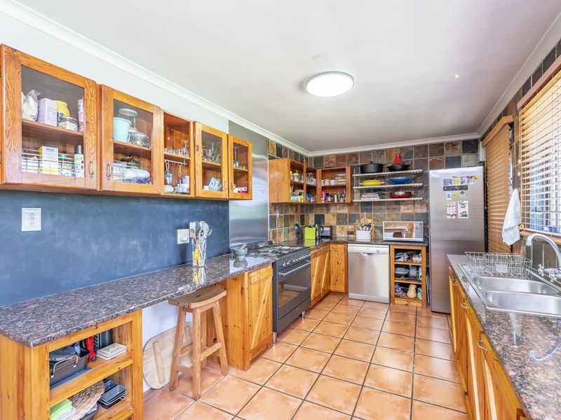 A functional kitchen featuring granite countertops, wooden cabinetry, tiled backsplash, and integrated appliances, offering a classic layout with ample storage space.