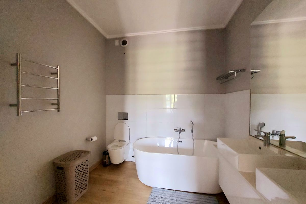 Modern bathroom featuring a freestanding bathtub, wall-mounted toilet, and a double vanity with a large mirror and heated towel rail.