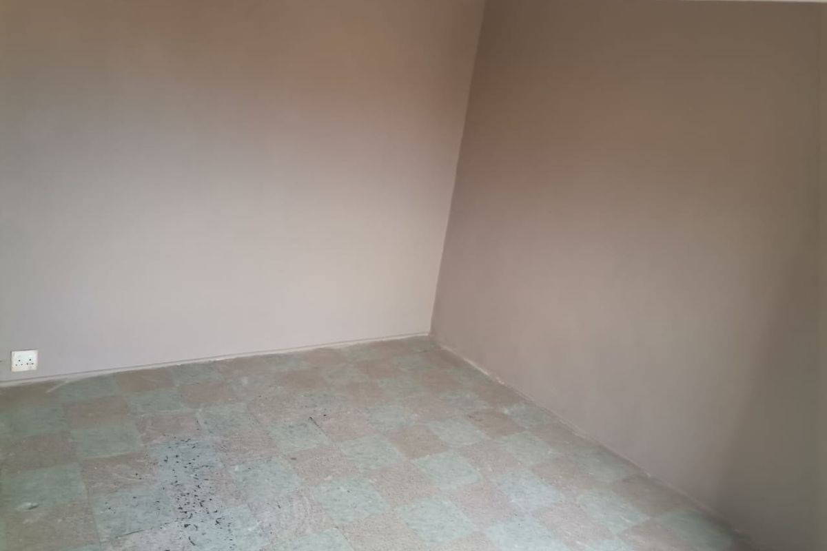 An empty bedroom featuring neutral painted walls and tiled flooring, providing a blank canvas for potential renovation or interior design updates.