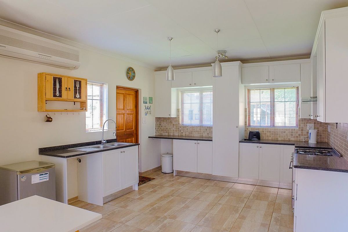 A well-maintained kitchen featuring white cabinetry, granite countertops, tiled flooring, and a gas hob, offering a functional and bright workspace.