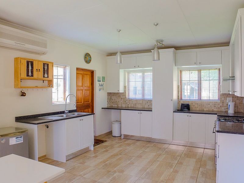 A well-maintained kitchen featuring white cabinetry, granite countertops, tiled flooring, and a gas hob, offering a functional and bright workspace.