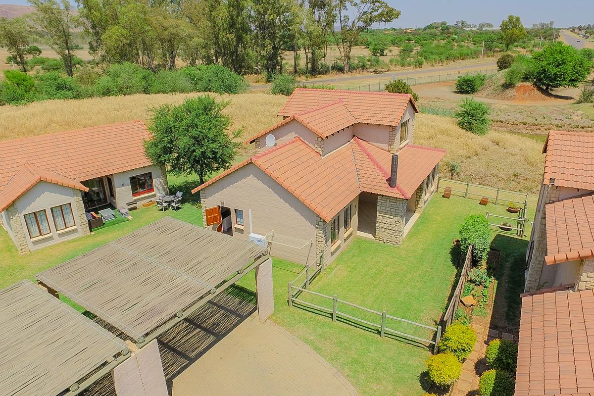 Aerial view of a townhouse complex featuring terracotta tiled roofs, stone cladding accents, timber pergolas, and well-maintained garden spaces.
