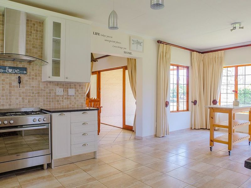 Open-plan kitchen and living area featuring tiled flooring, granite countertops, a gas stove with extractor fan, and direct access to an outdoor patio.
