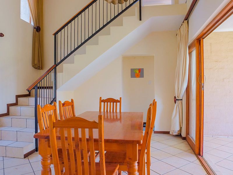 Dining area featuring tiled flooring, a staircase with a metal balustrade, and sliding glass doors leading to an outdoor space.