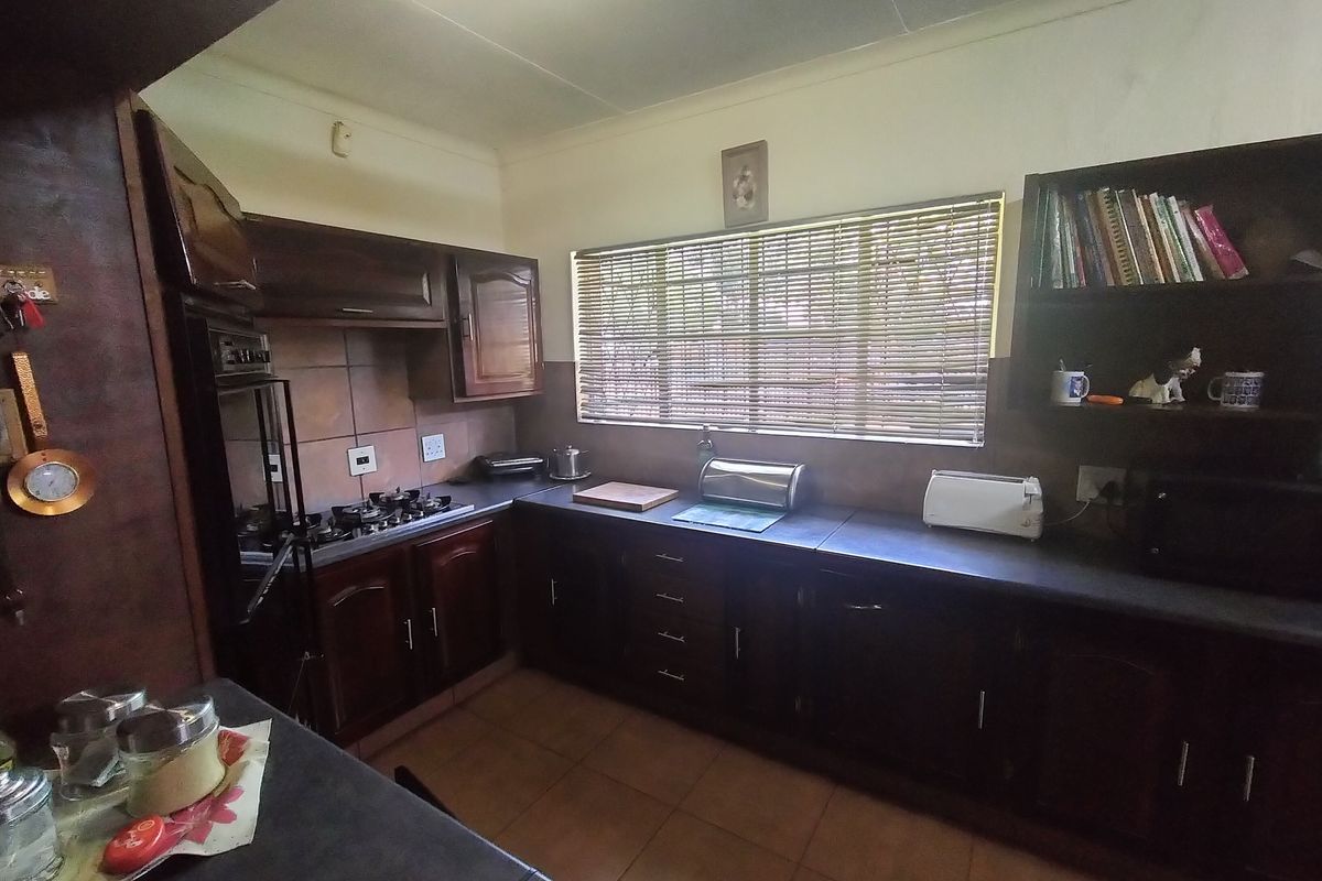 A functional kitchen featuring dark wood cabinetry, a gas hob, built-in oven, and tiled splashbacks, offering a traditional layout with ample storage space.