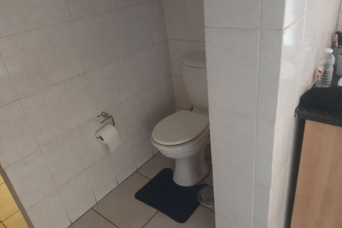 A functional bathroom featuring tiled walls and flooring with a standard toilet installation.