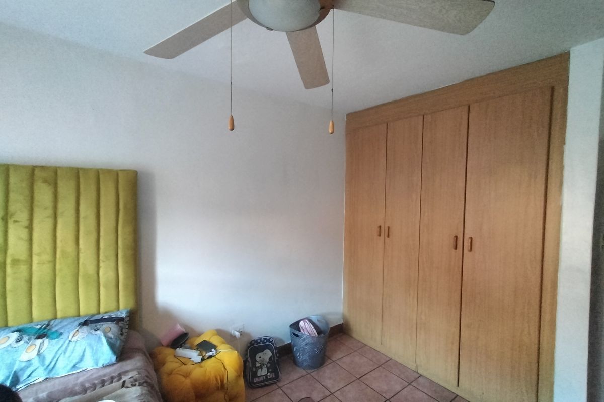 Bedroom featuring a ceiling fan, built-in wooden wardrobe, and tiled flooring.
