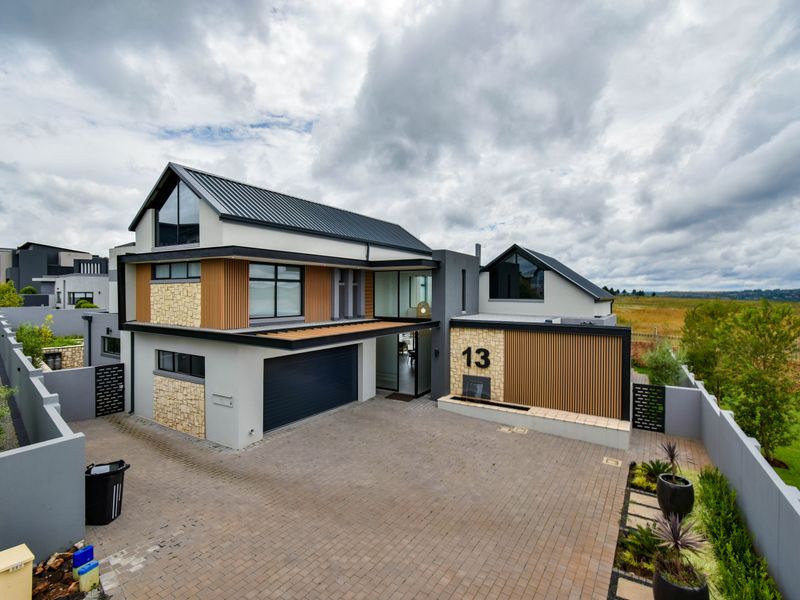 Modern double-storey residence featuring a contemporary mix of stone, timber, and metal finishes with a spacious paved driveway and integrated garage.