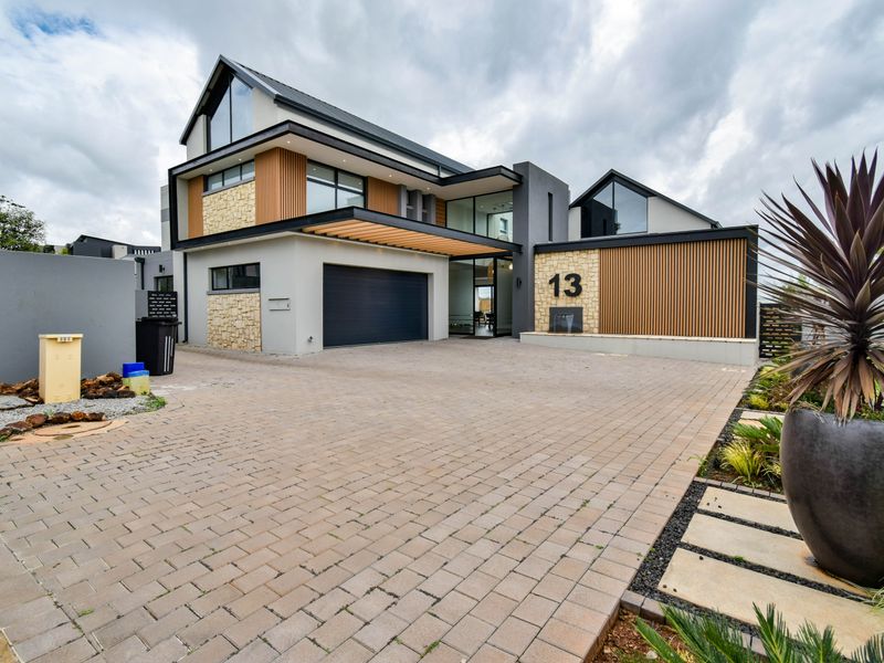 Modern architectural front elevation featuring stone and timber accents, a paved driveway, and a double garage entrance.