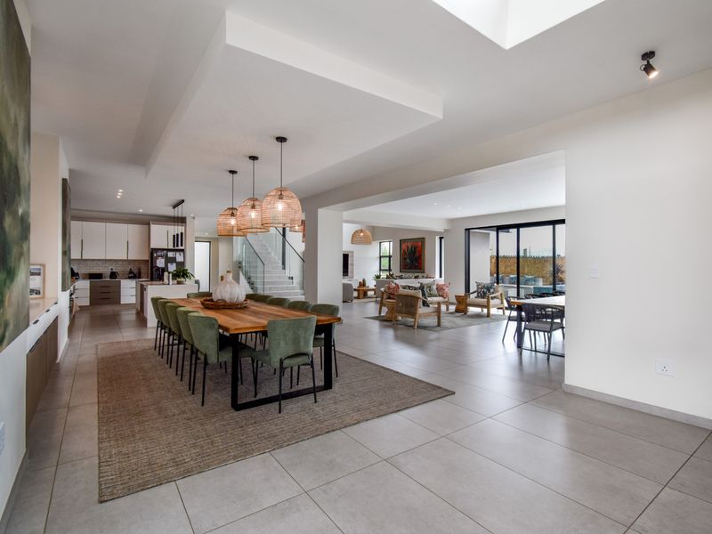 Spacious open-plan living area featuring a modern kitchen, dining space, and seamless flow to the outdoor patio through large sliding glass doors.