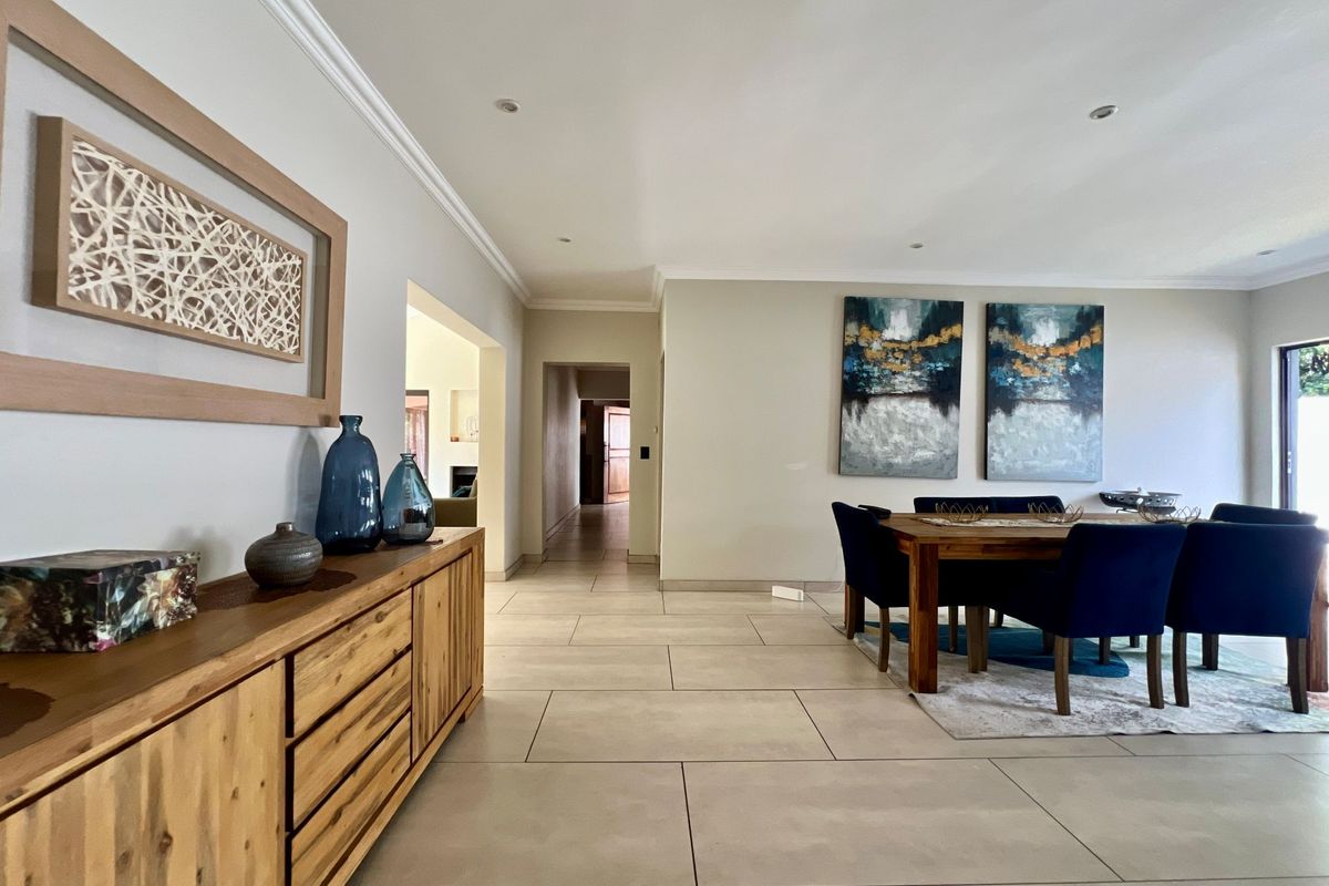 A spacious, well-maintained living and dining area featuring neutral tiled flooring, recessed lighting, and elegant cove cornicing throughout the open-plan space.