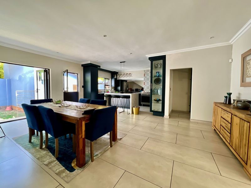 Spacious open-plan living and dining area featuring modern kitchen cabinetry, a central island, tiled floors, and direct access to the outdoor patio.