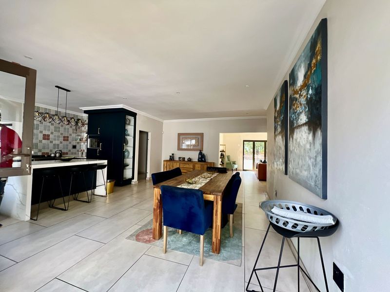 Spacious open-plan living area featuring a modern kitchen with a central island, tiled flooring, and seamless flow into the dining space.