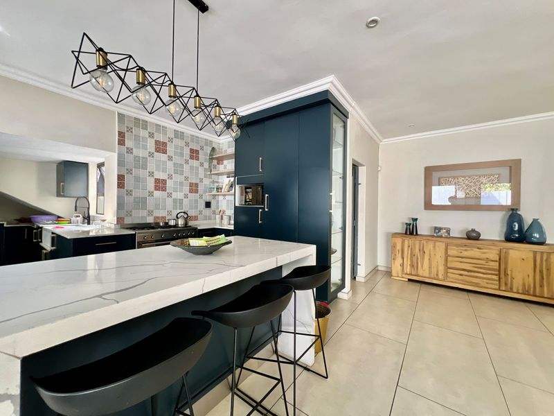 Modern kitchen featuring a stone island, dark cabinetry, gas stove, and decorative tiled backsplash, creating a stylish and functional culinary space.