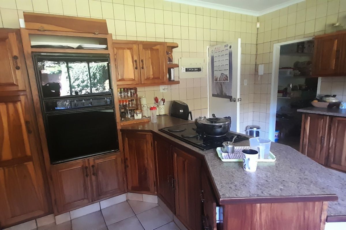 A functional kitchen featuring traditional wooden cabinetry, built-in oven, electric hob, and tiled finishes, offering a classic layout with potential for modern updates.