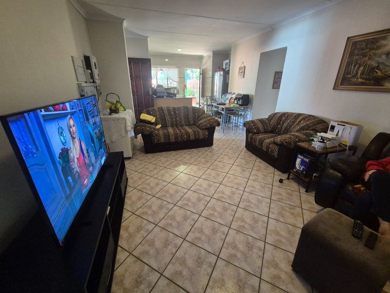 Open-plan living area featuring ceramic floor tiles and coved cornicing, providing a functional space that connects to the kitchen area.
