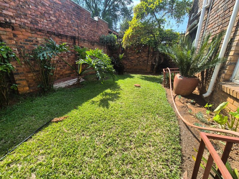 A private rear garden area featuring a well-maintained lawn enclosed by traditional brick boundary walls.
