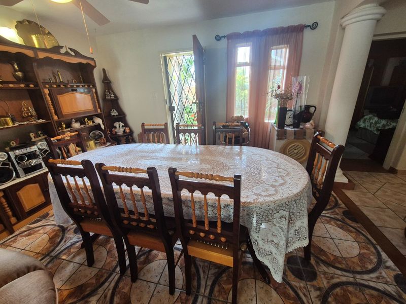 A dining room featuring patterned ceramic tile flooring, a decorative column, and direct access to the exterior through a security gate.