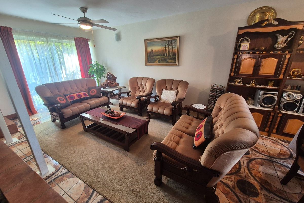 A living room featuring tiled flooring, a ceiling fan, and a large sliding glass door providing natural light.