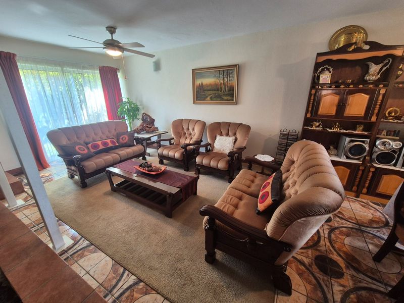 A living room featuring tiled flooring, a ceiling fan, and a large sliding glass door providing natural light.