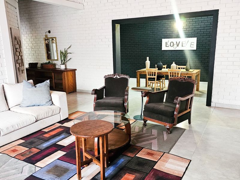 Spacious open-plan living and dining area featuring painted brick walls, neutral tiled flooring, and a distinct architectural transition between the two zones.