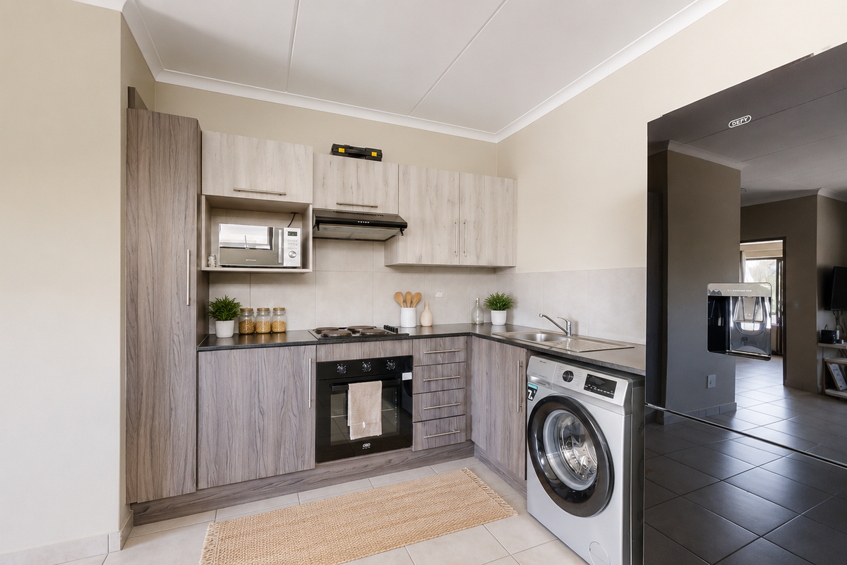 Modern kitchen featuring wood-grain cabinetry, integrated appliances, electric hob, oven, and a convenient built-in washing machine space.